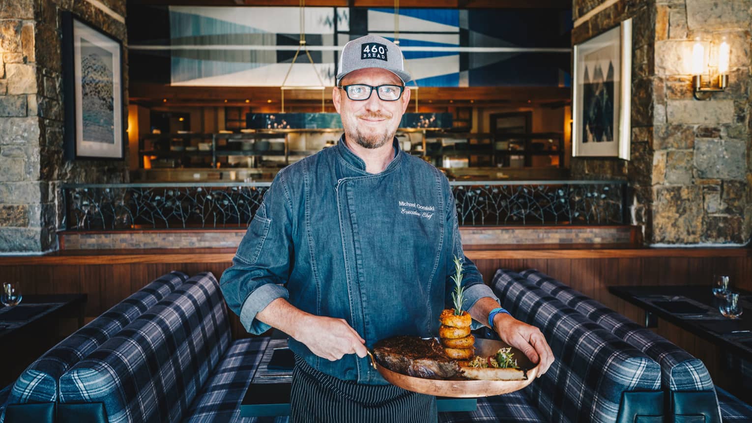 Michael Goralski holds a tray with stacked onion rings and a cut of beef
