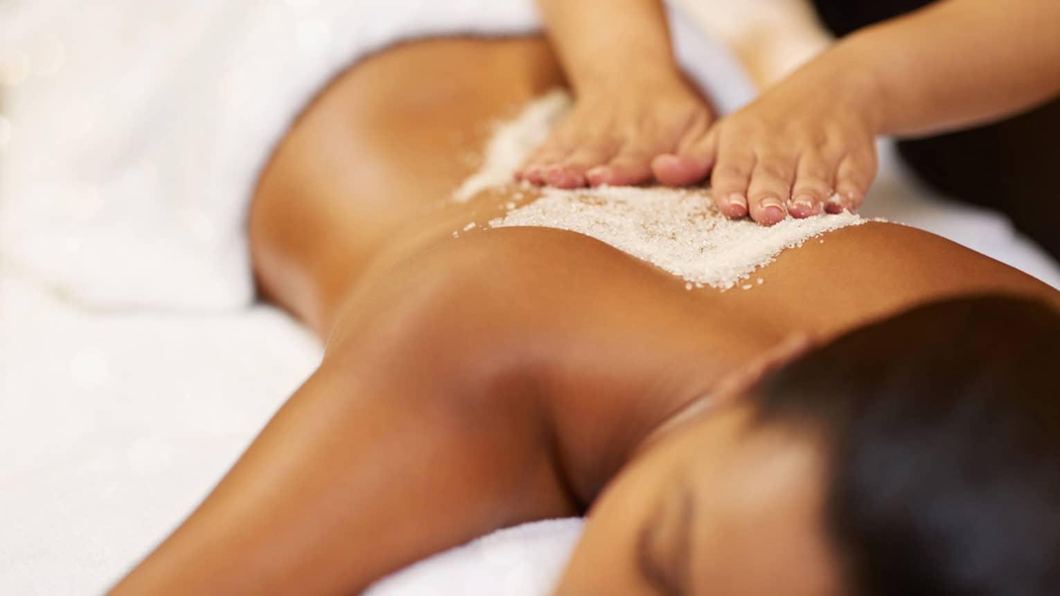 A young woman receives an exfoliating treatment at the spa