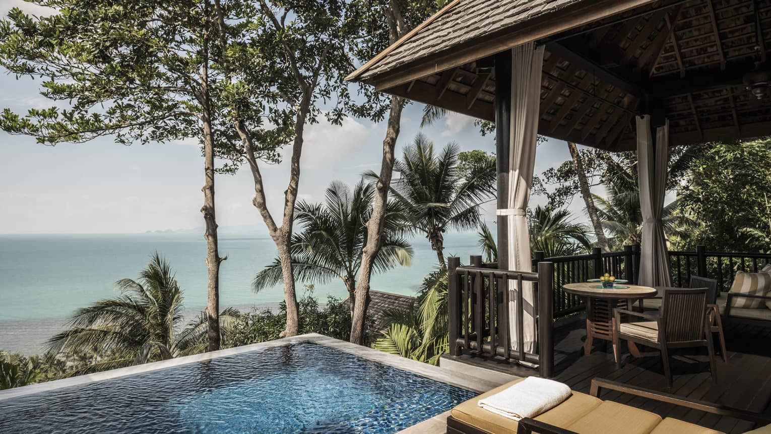 Premier One-Bedroom Pool Villa patio with chairs, table by plunge swimming pool with ocean views