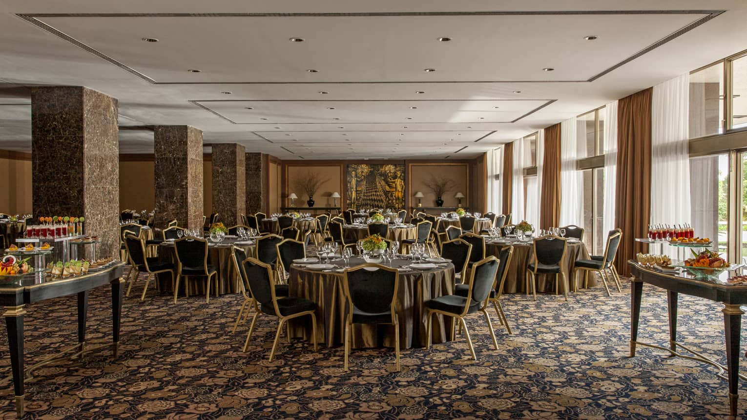 Round banquet tables in large, sunny banquet room with marble pillars