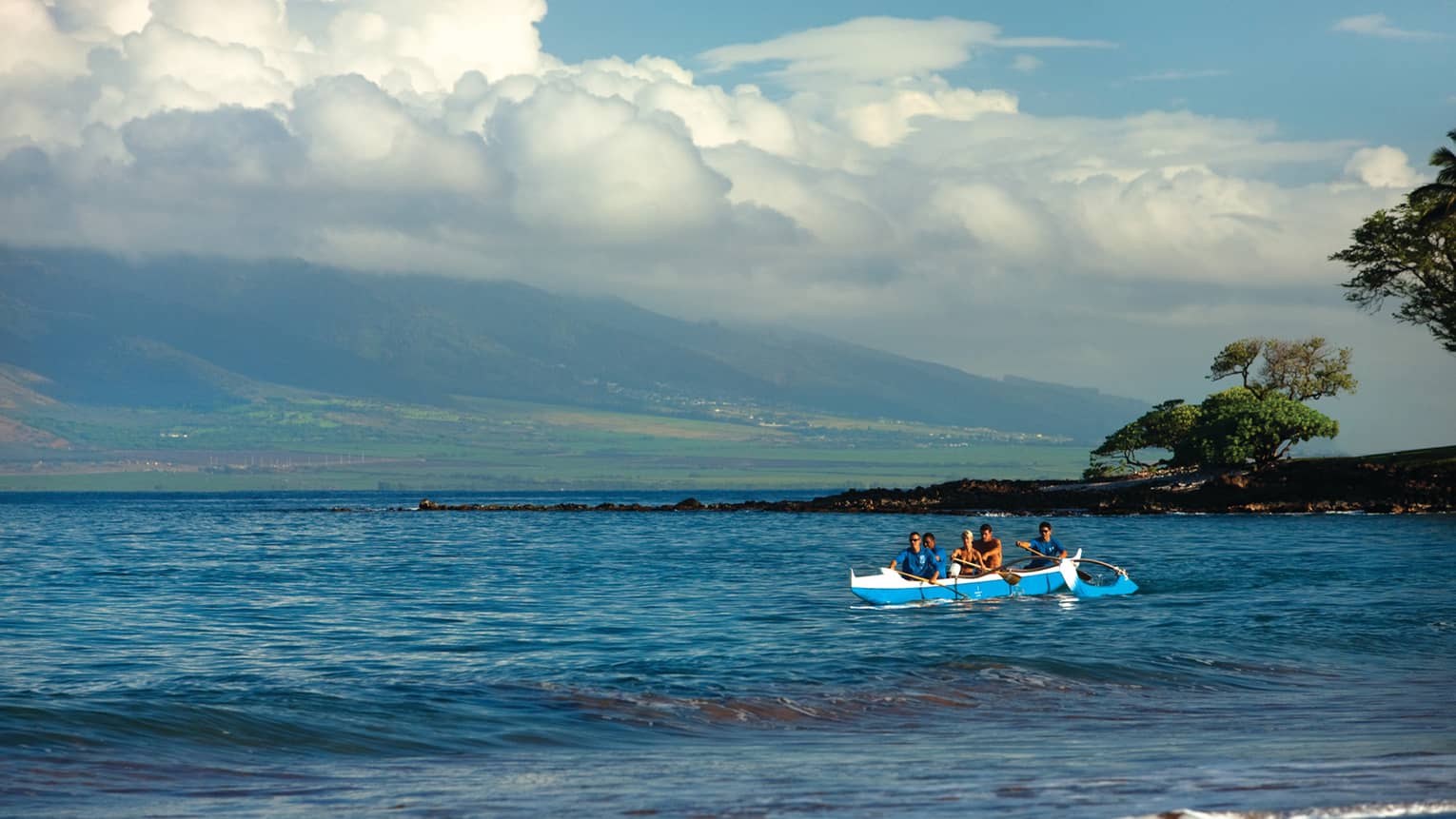 Group of people arrive on shore in an outrigger canoe