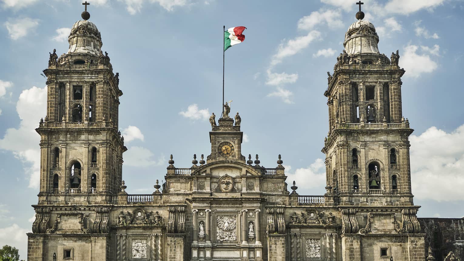 Historic Mexico City building, towers with flag against blue sky
