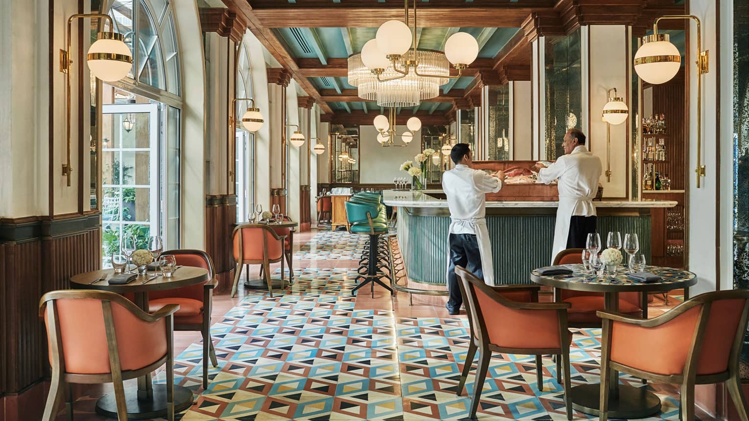 Pink dining chairs, wood tables, colourful tiles in bright Zanaya Restaurant dining room