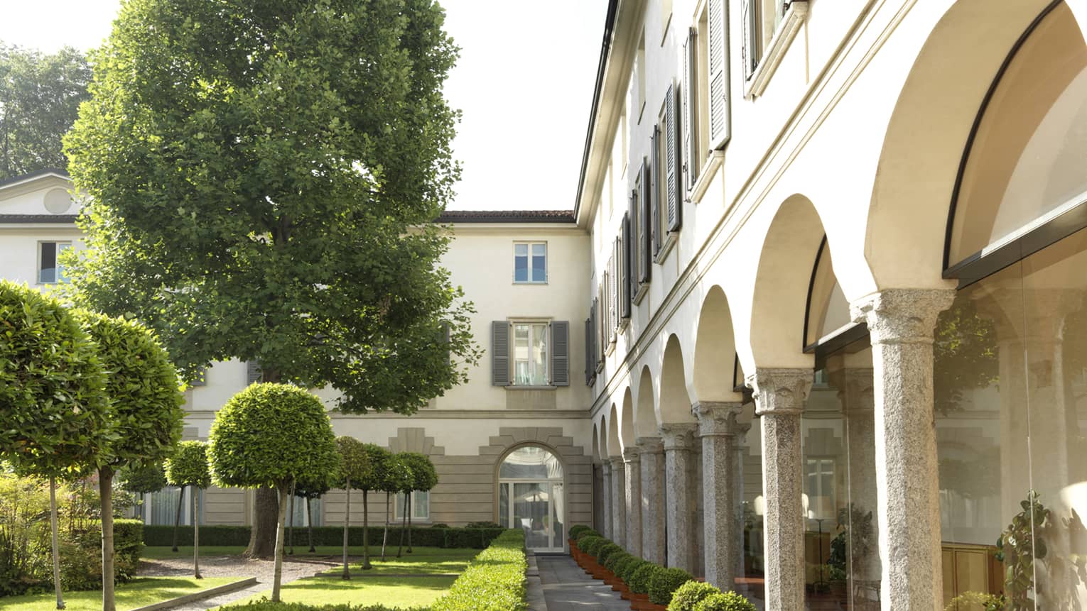 Historic 1990s photo of Four Seasons Hotel, pillars around courtyard with shrubs, trees