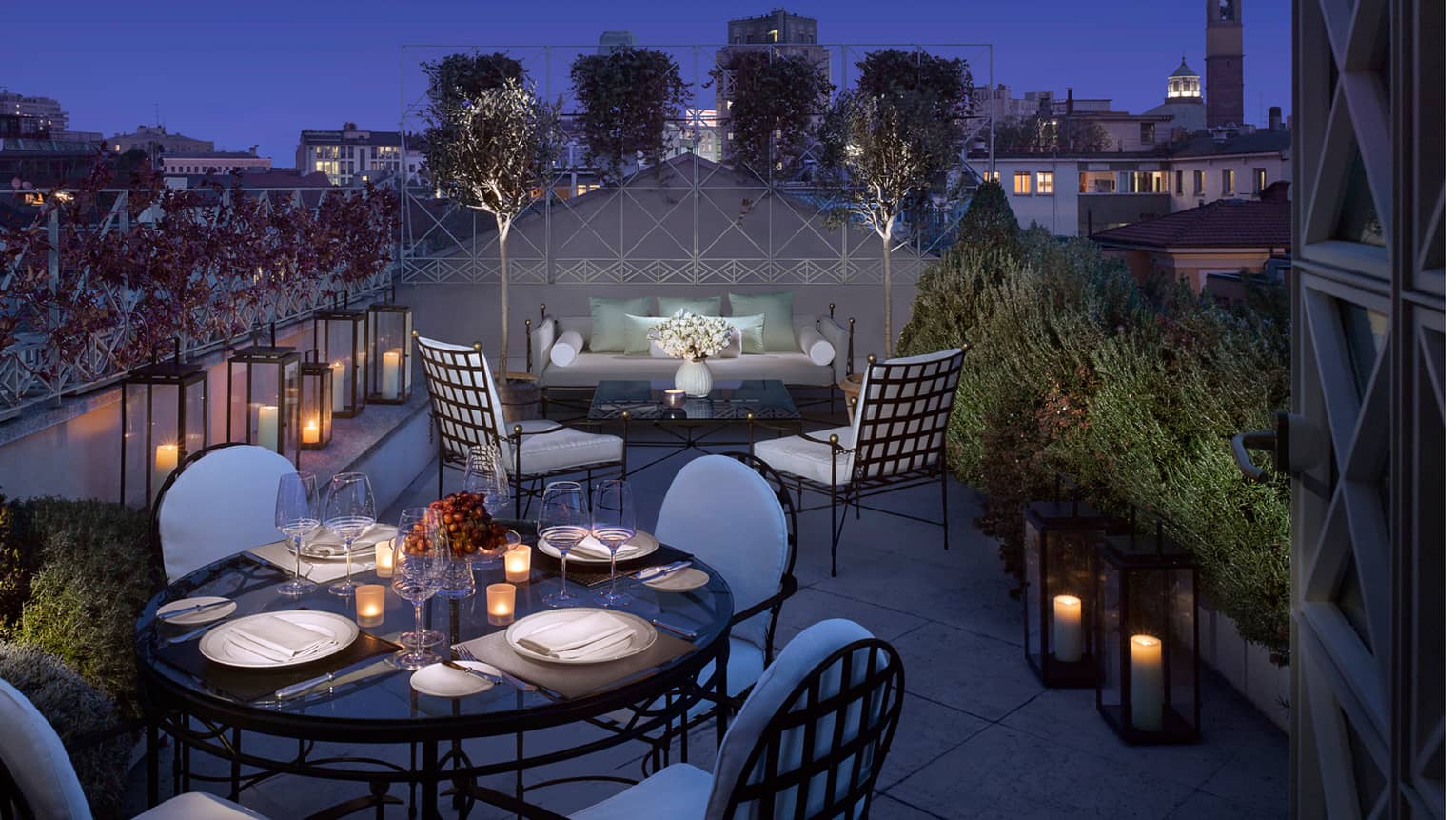 Penthouse Suite lantern-lined rooftop balcony, candle-lit dining table, patio sofa and chairs at night