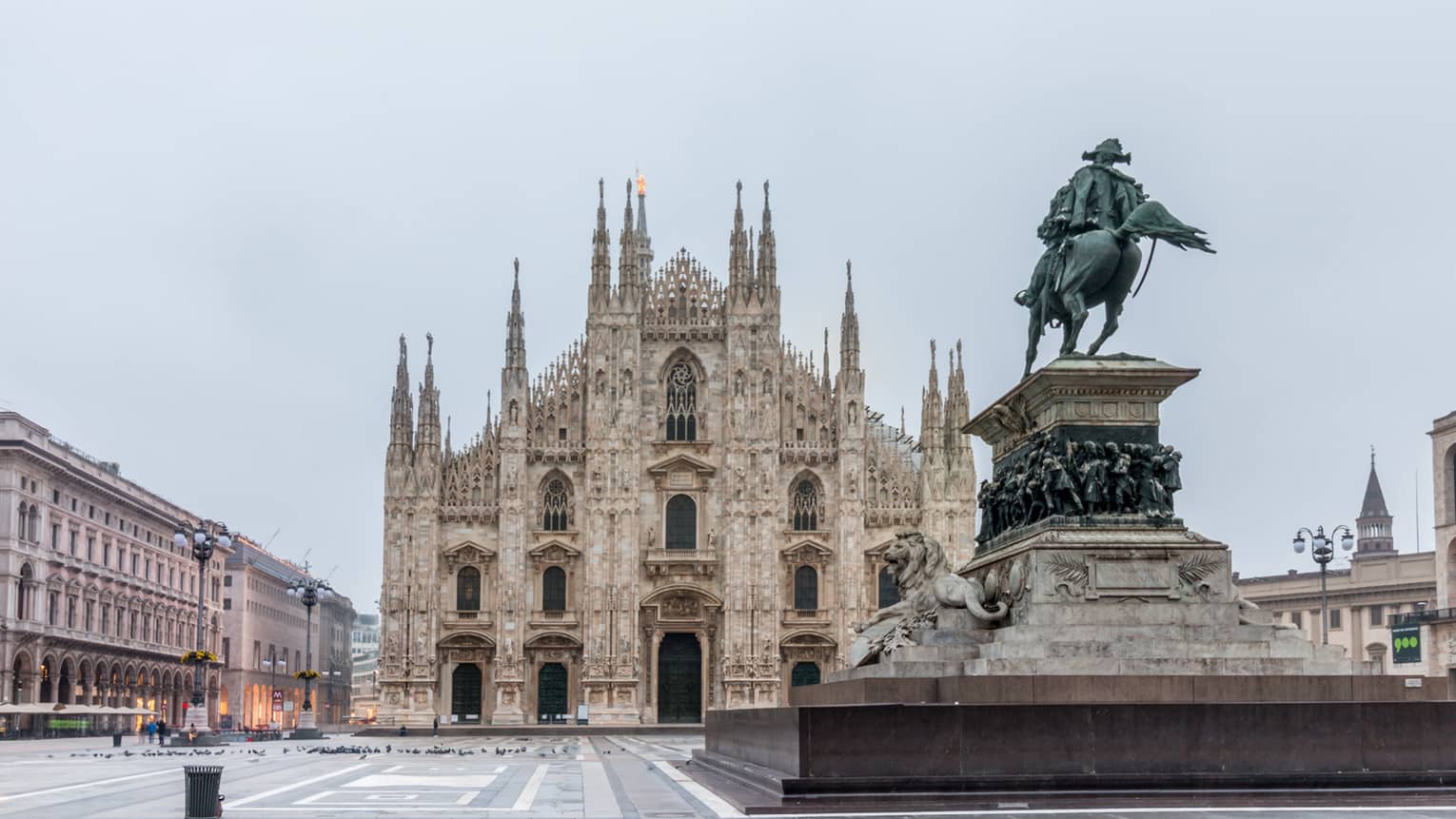 Rear view of the sculpture of King Victor Emmanuel II facing the grand façade of Milan's dome cathedral across the piazza.