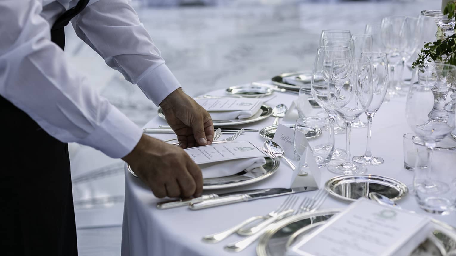 Wedding reception, hotel staff sets paper menu on banquet table with white linens 