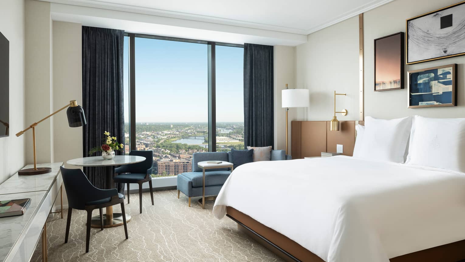 Hotel room with king bed, windowside chaise, and table with two chairs
