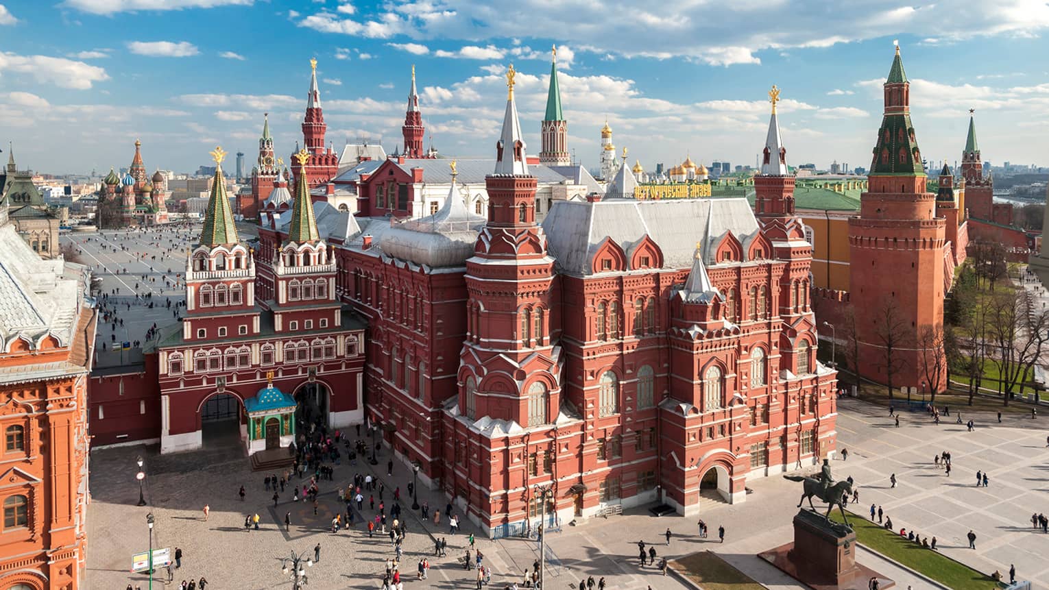 People walking in front of the State Historical Museum in Moscow's Red Square on sunny day