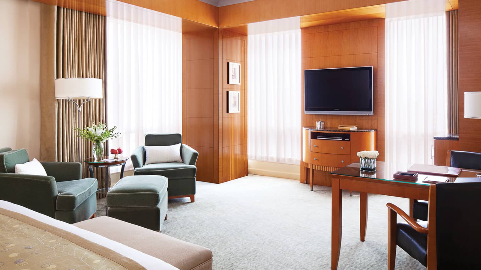 Executive Premier Room wood panel walls, sunny windows with sheer curtains, bed, TV, chairs
