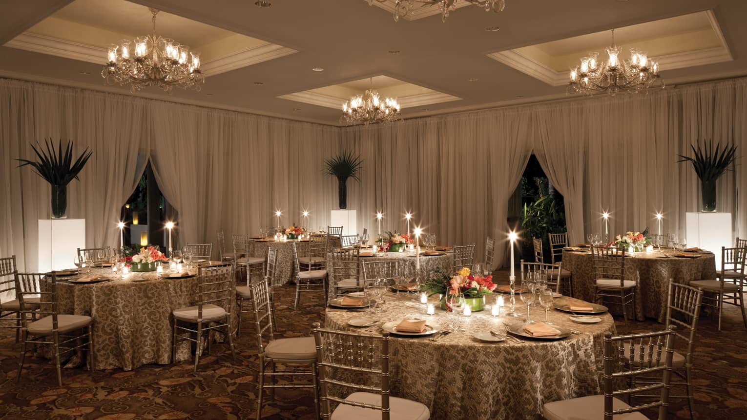 Round candle-lit banquet dining tables in ballroom