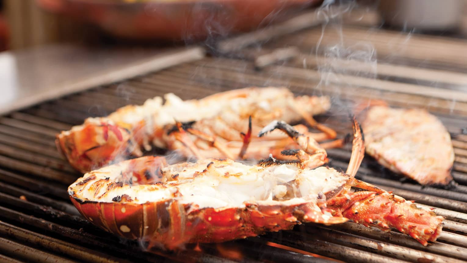 A lobster grilling on a barbecue, surrounded by rising smoke
