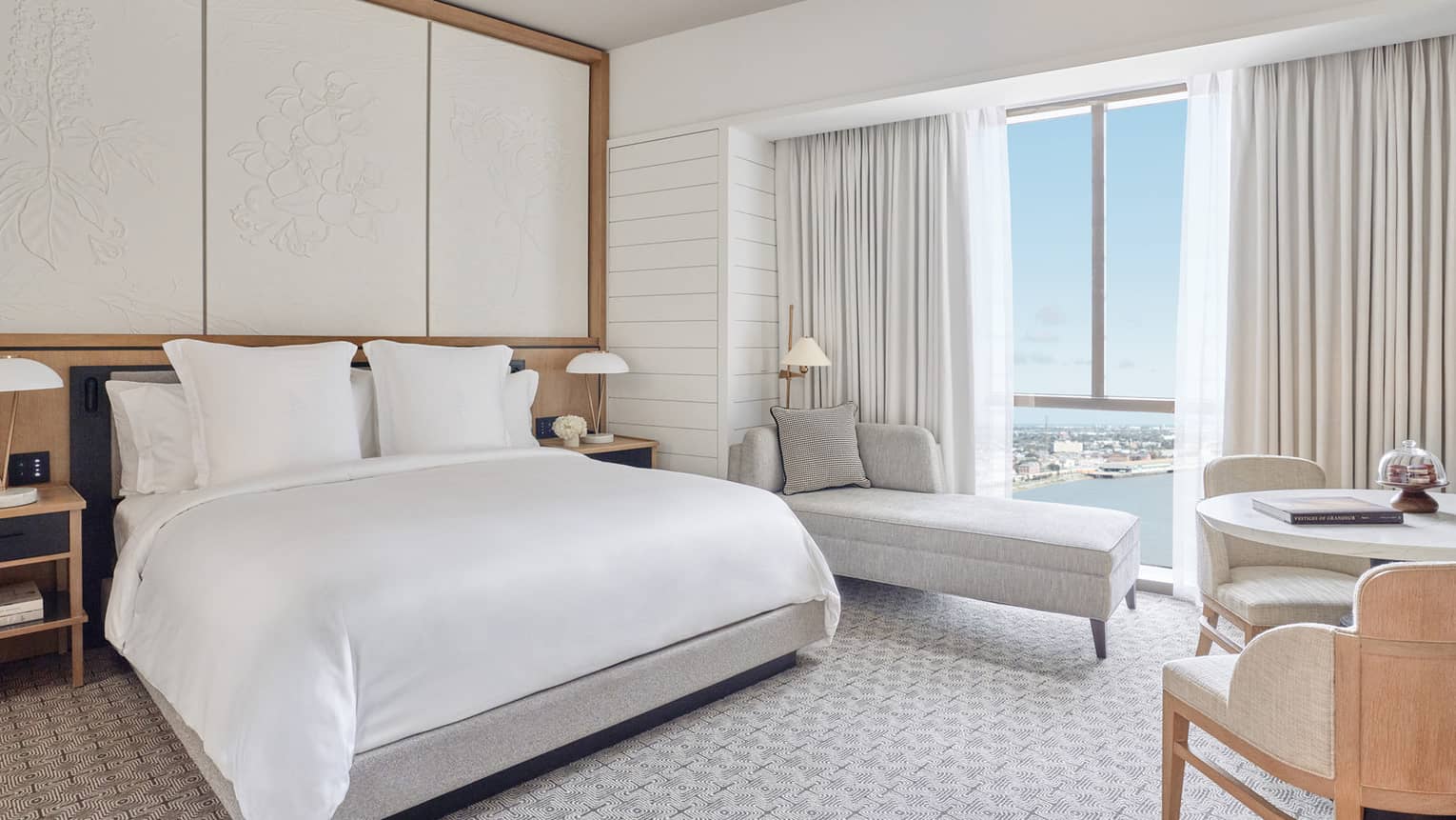 New Orleans hotel room bed, chaise and table by floor to ceiling window