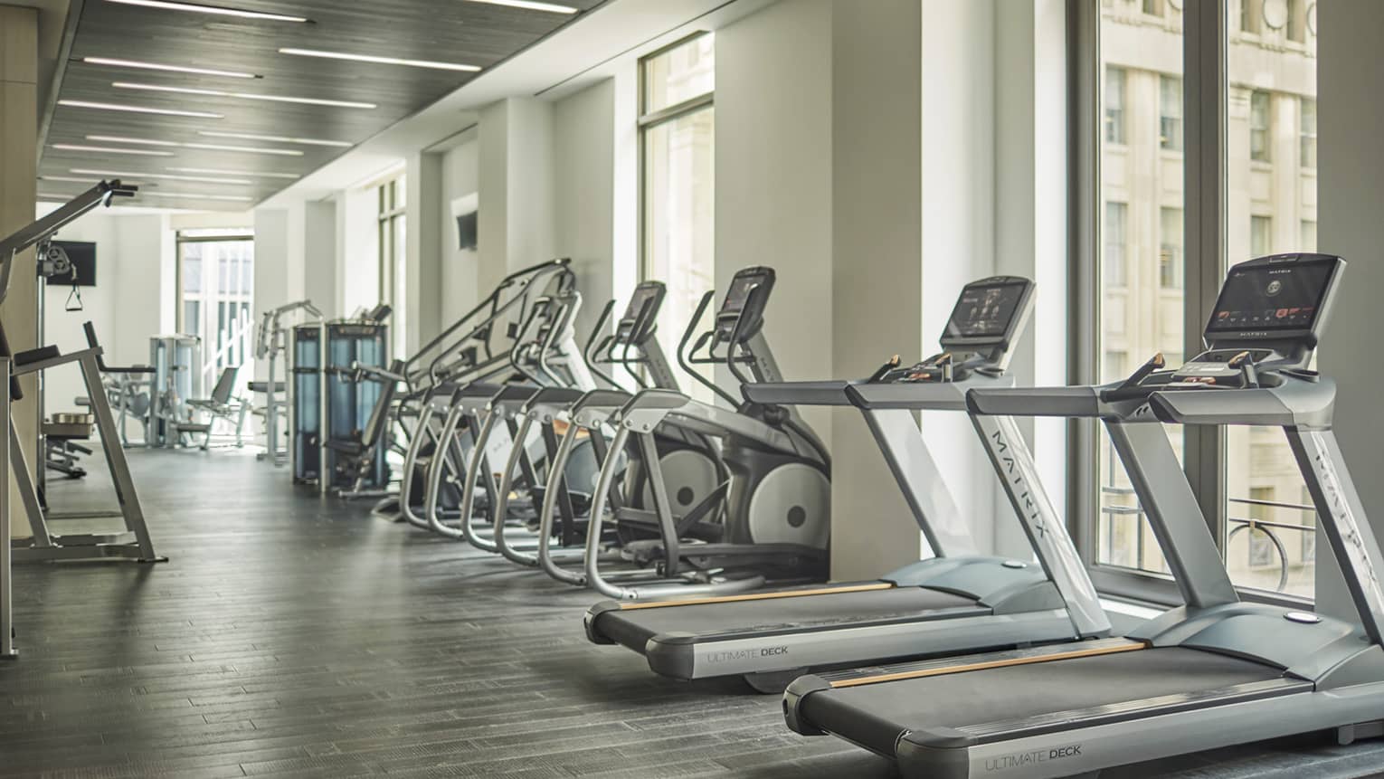 Treadmills, cardio machines in row by windows in Fitness Centre