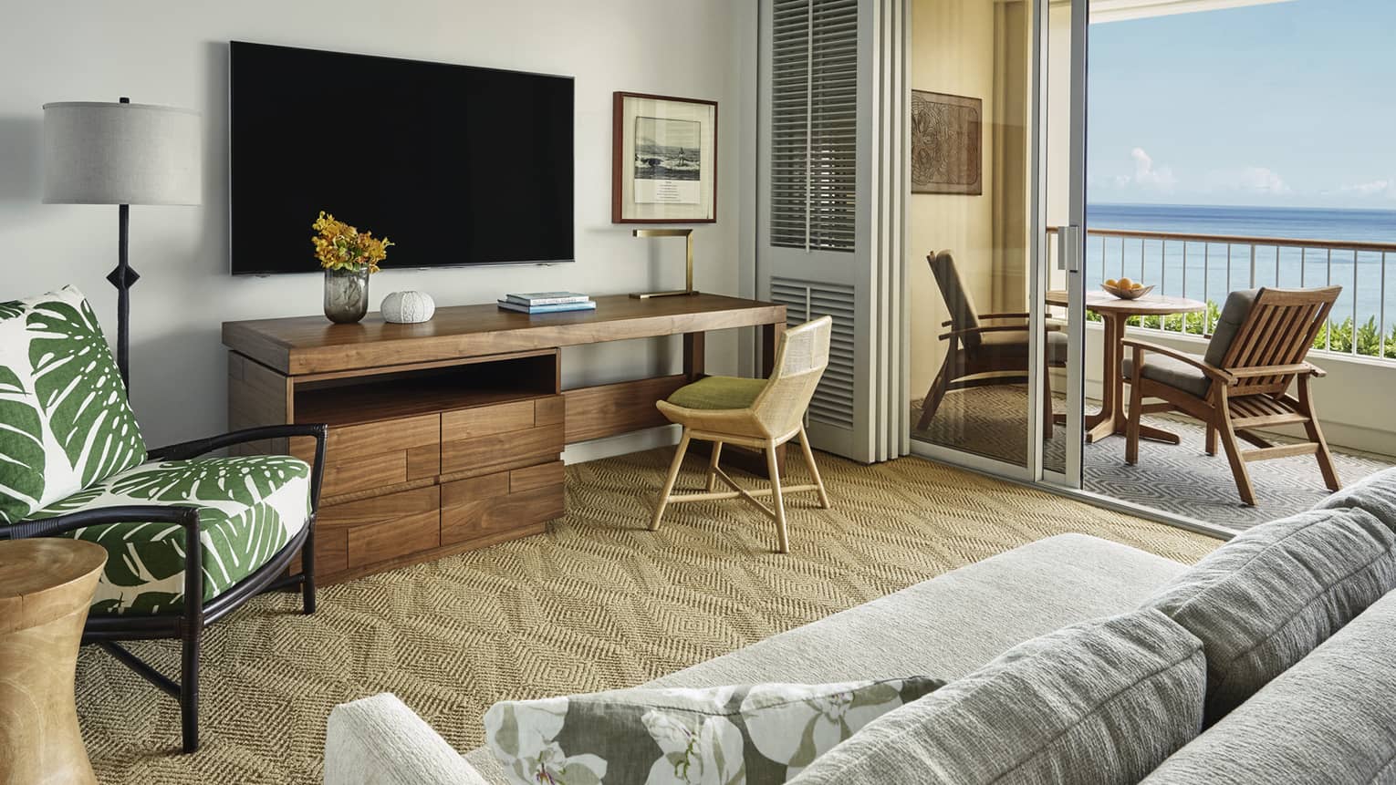Oceanfront Suite large rustic wood desk under TV, palm print chair, open balcony doors