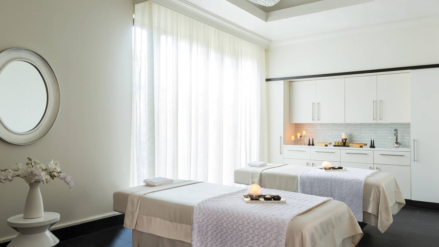Couples Suite two massage tables with trays with glowing candles, salts in spa treatment room