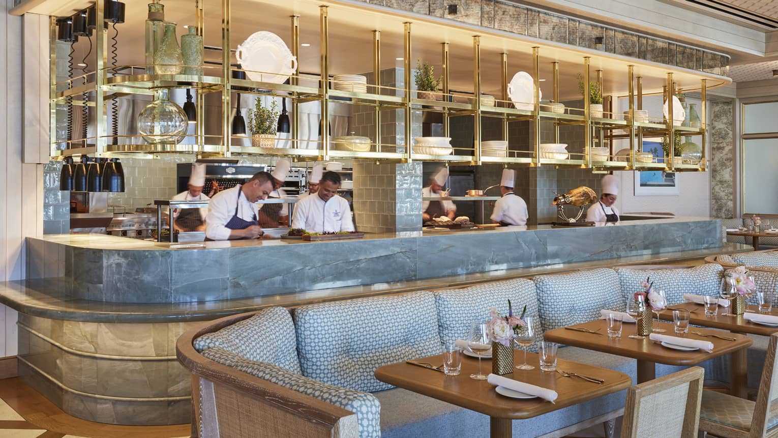 Staff members behind Flories curved blue marble bar, blue banquette seating