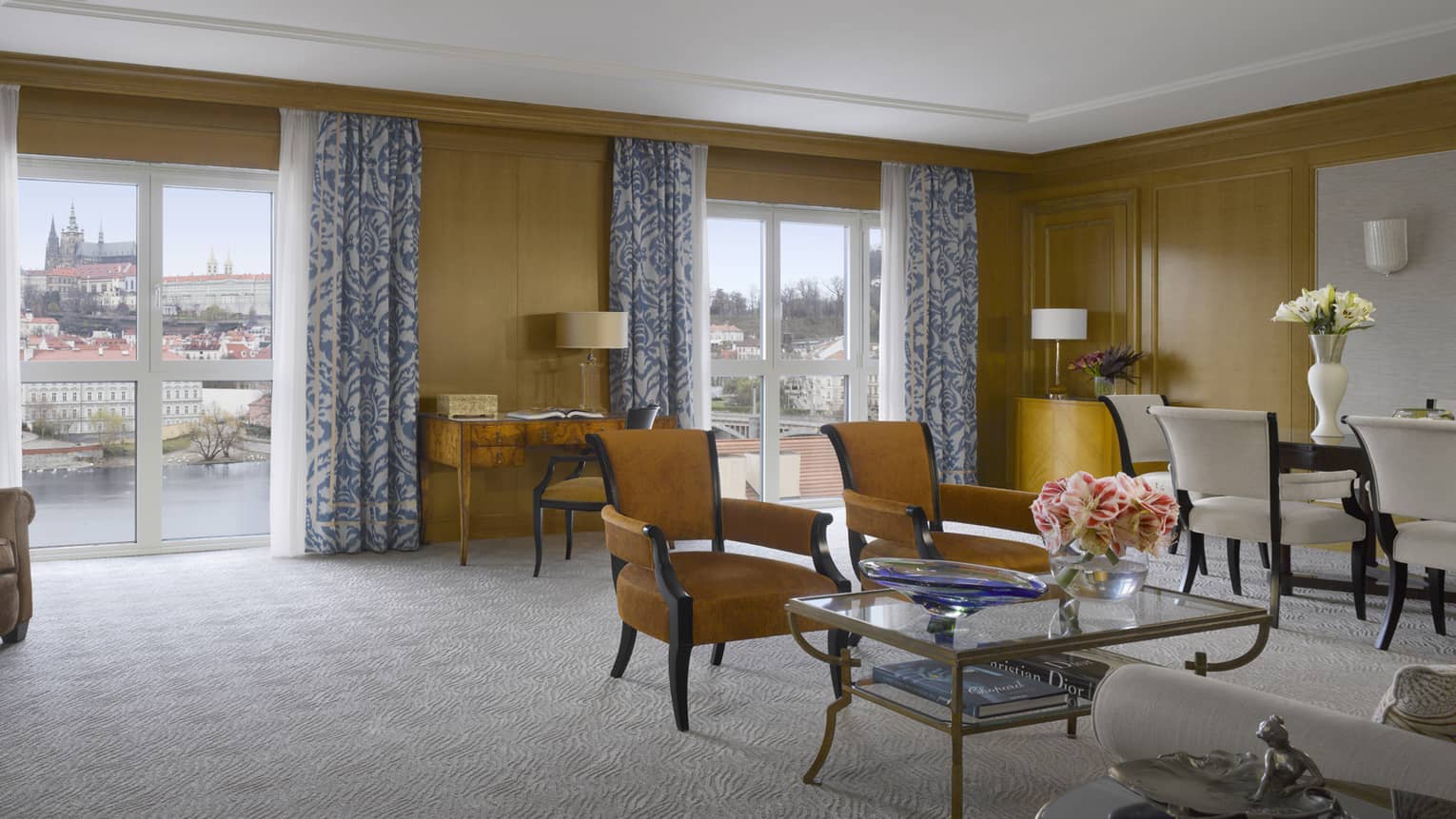 Spacious Premier Suite seating area with tan chairs, sunny windows