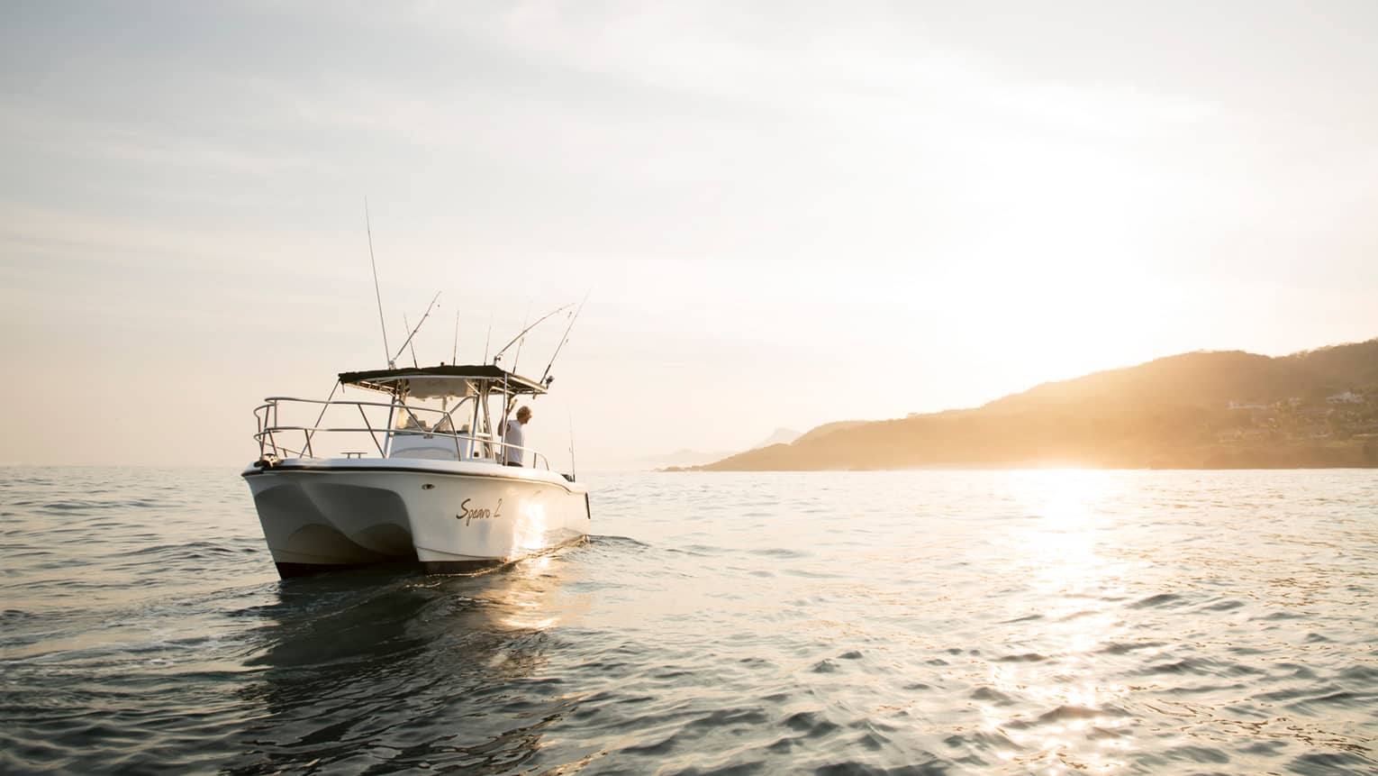 White deep-sea fishing charter fishing boat on water at sunrise 