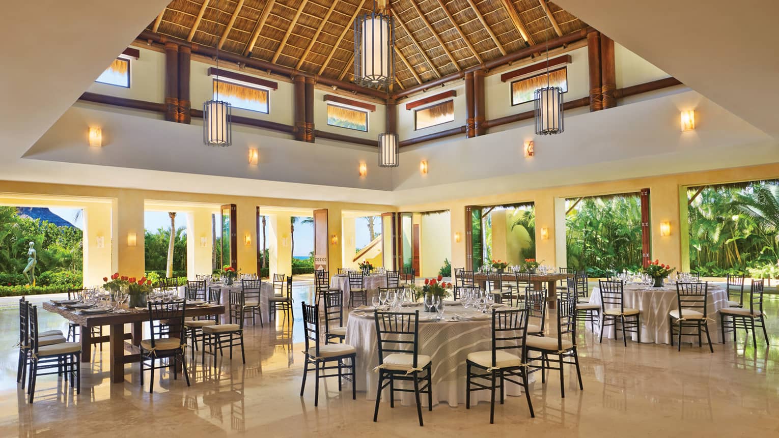 Banquet tables under pyramid roof, lanterns in open air event space 
