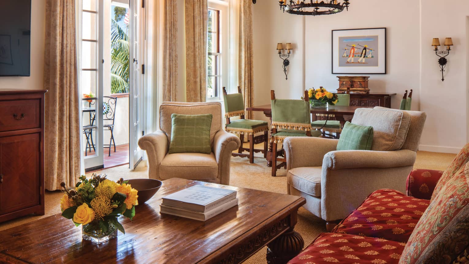 Sunny dining and seating area with open patio door, plush armchairs, wood table