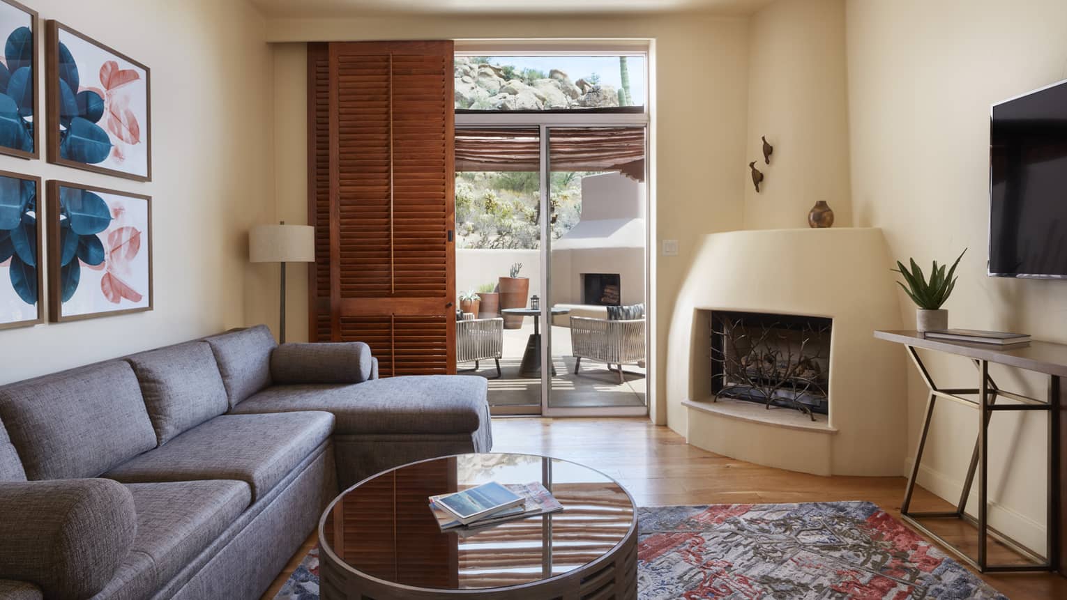 Living room with fireplace, sofa, coffee table, wooden door opening up to patio