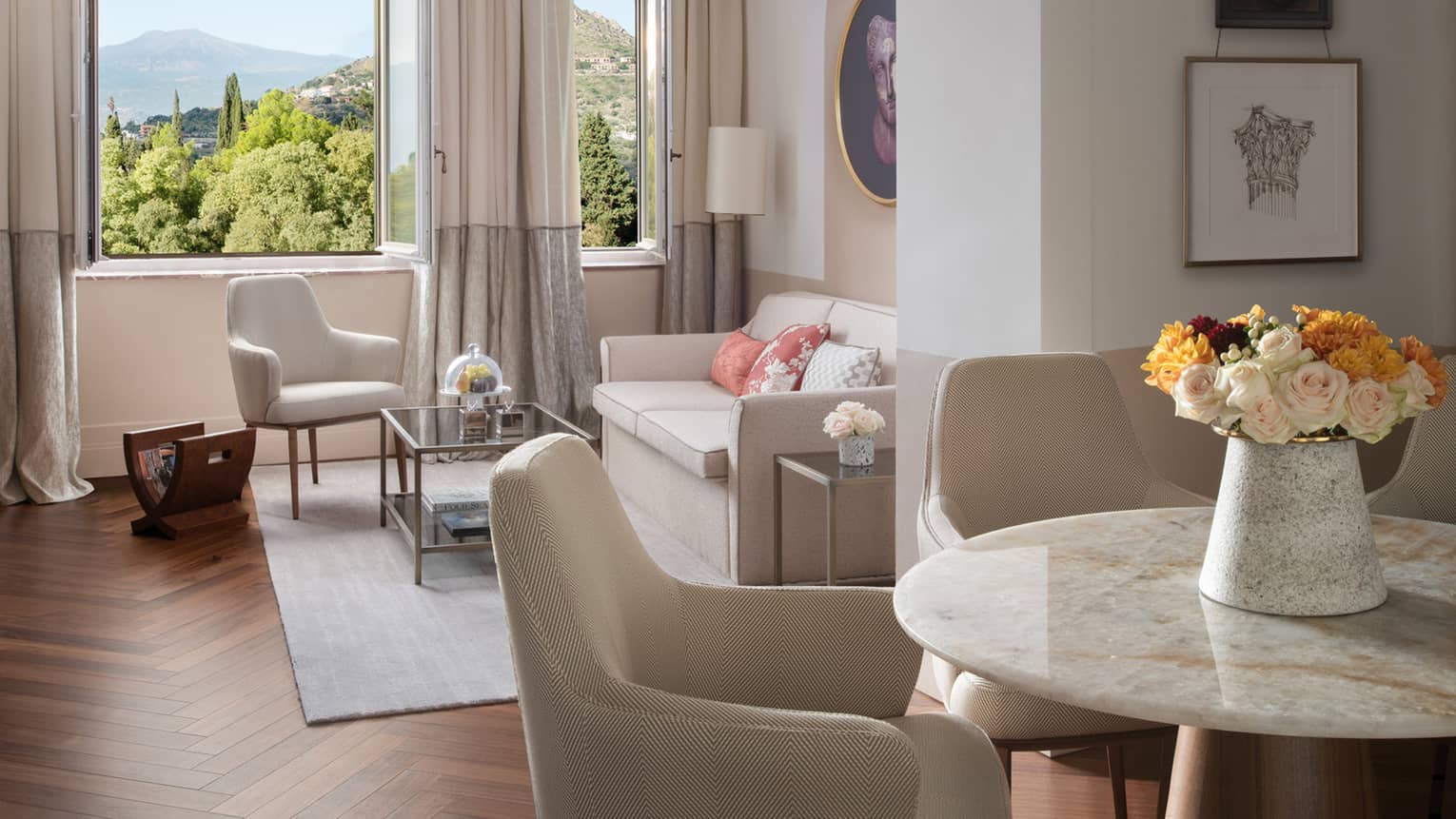 Round marble dining table, leather chairs, opening to living room with window