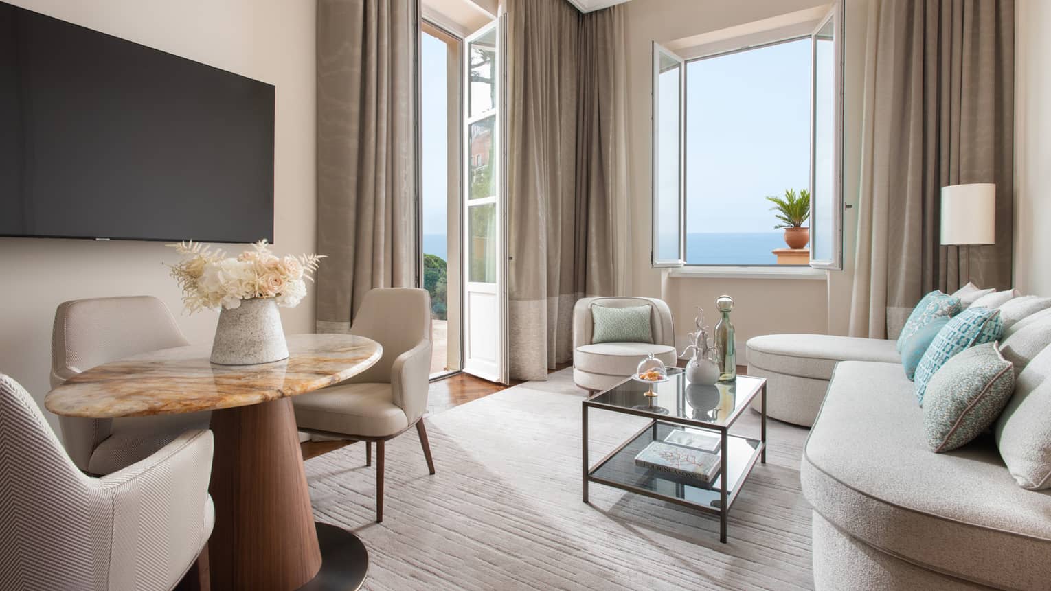 Living room with cream sofa, glass coffee table, dining set and sea-view windows