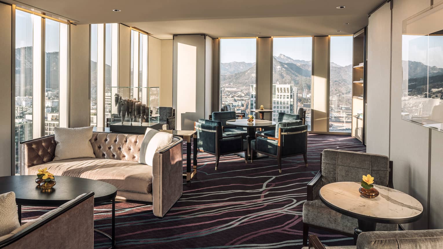 Lounge with tufted velvet sofas, cocktail tables and armchairs, floor-to-ceiling windows
