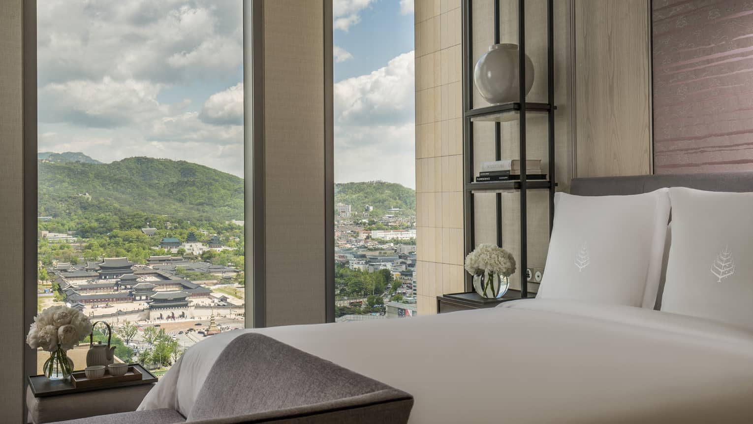 Palace-View Executive Suite bed, chaise at foot, shelf with vases, books beside window overlooking Gyeongbokgung Palace