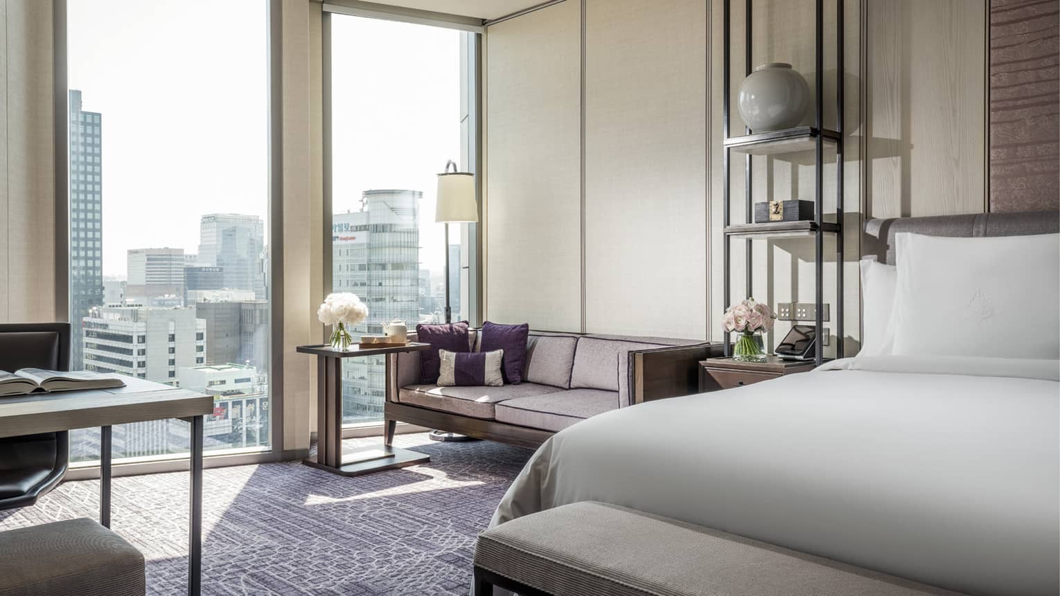 Premier Room bed with bench at foot, small sofa and table, flowers by large sunny windows, work desk