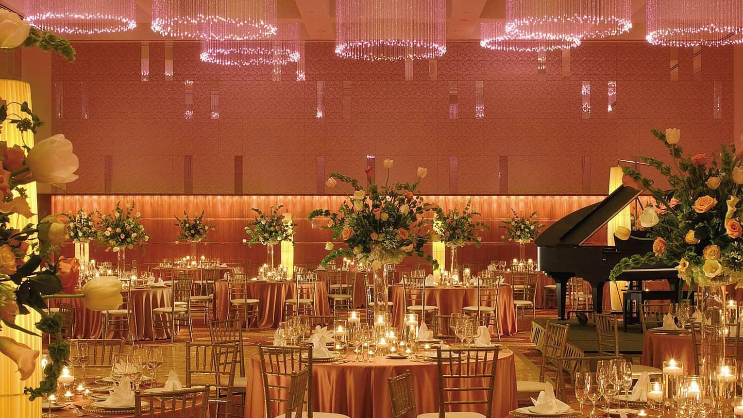 Ballroom banquet, candle-lit dining tables under round chandeliers with pink lights strings