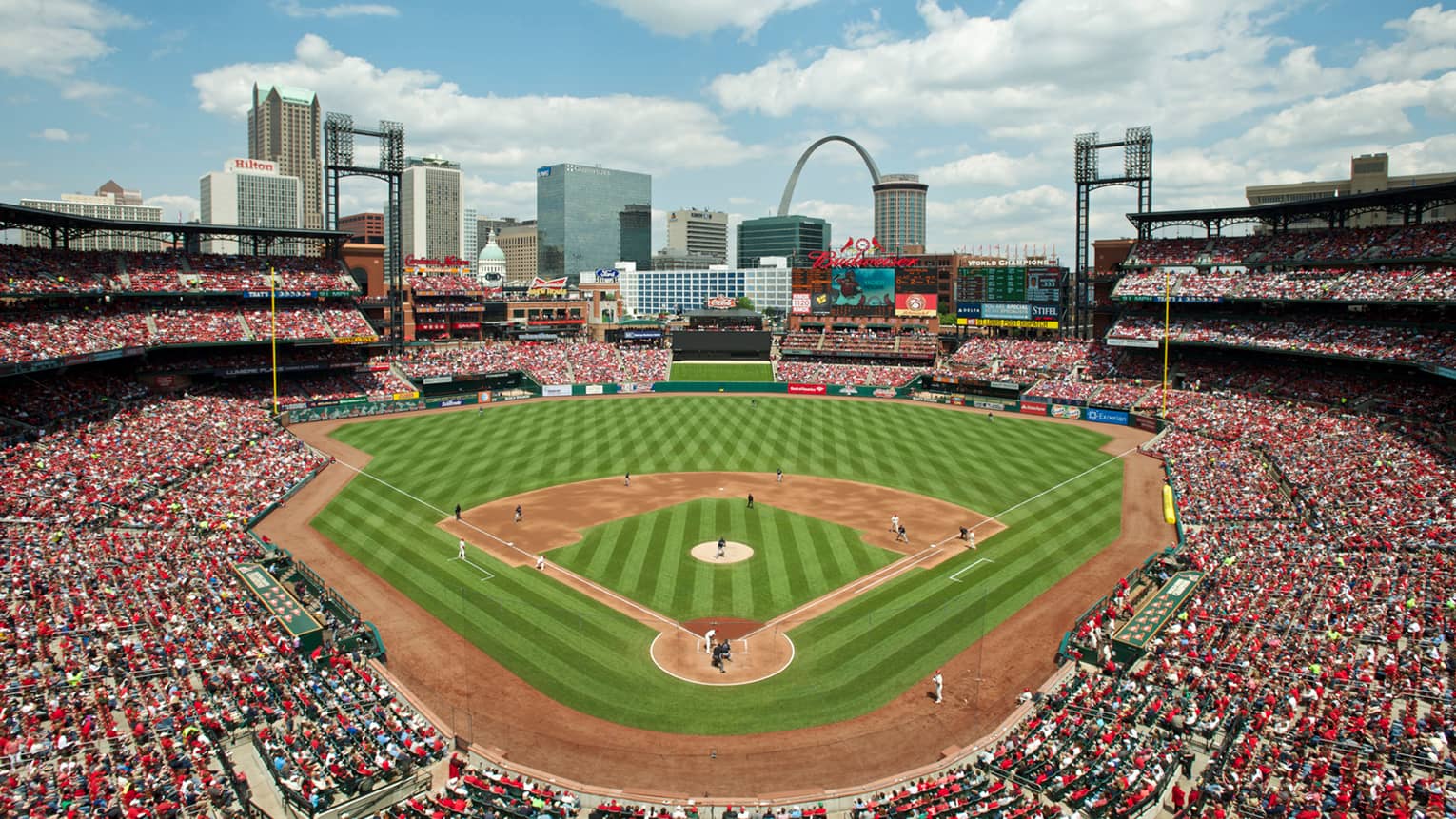 Aerial view of  sunny baseball field at Busch Stadium with large crowd in stands, city skyline around