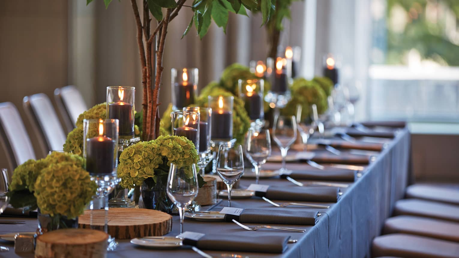 Black pillar candles in votives, green flowers, wine glasses along banquet table