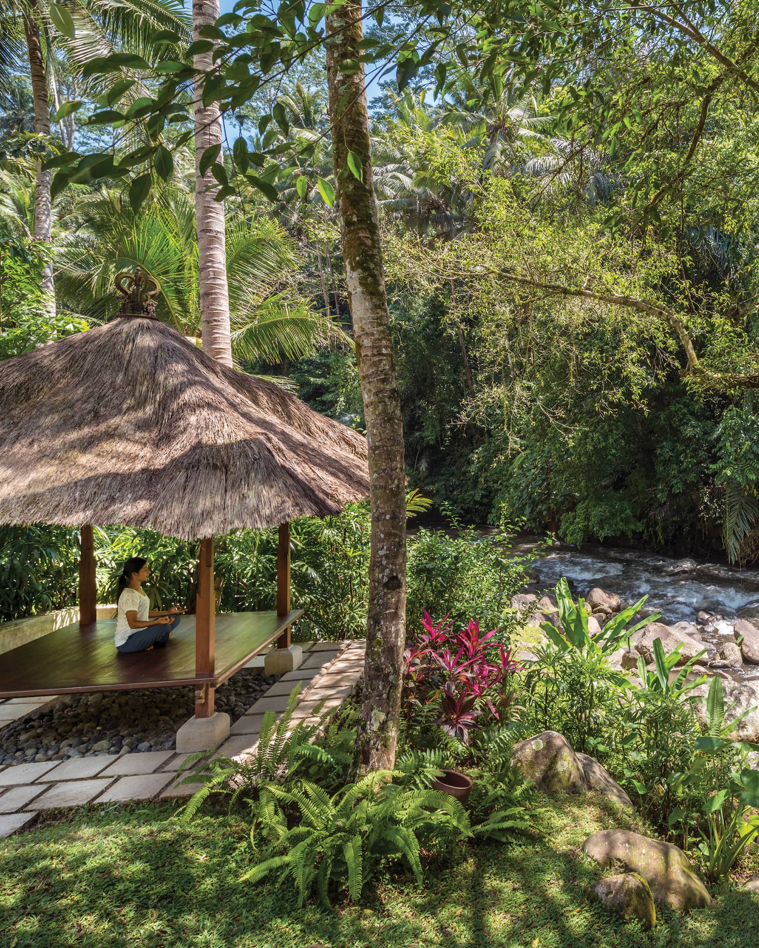 A guest meditating in a pavilion next to a flowing river in Bali