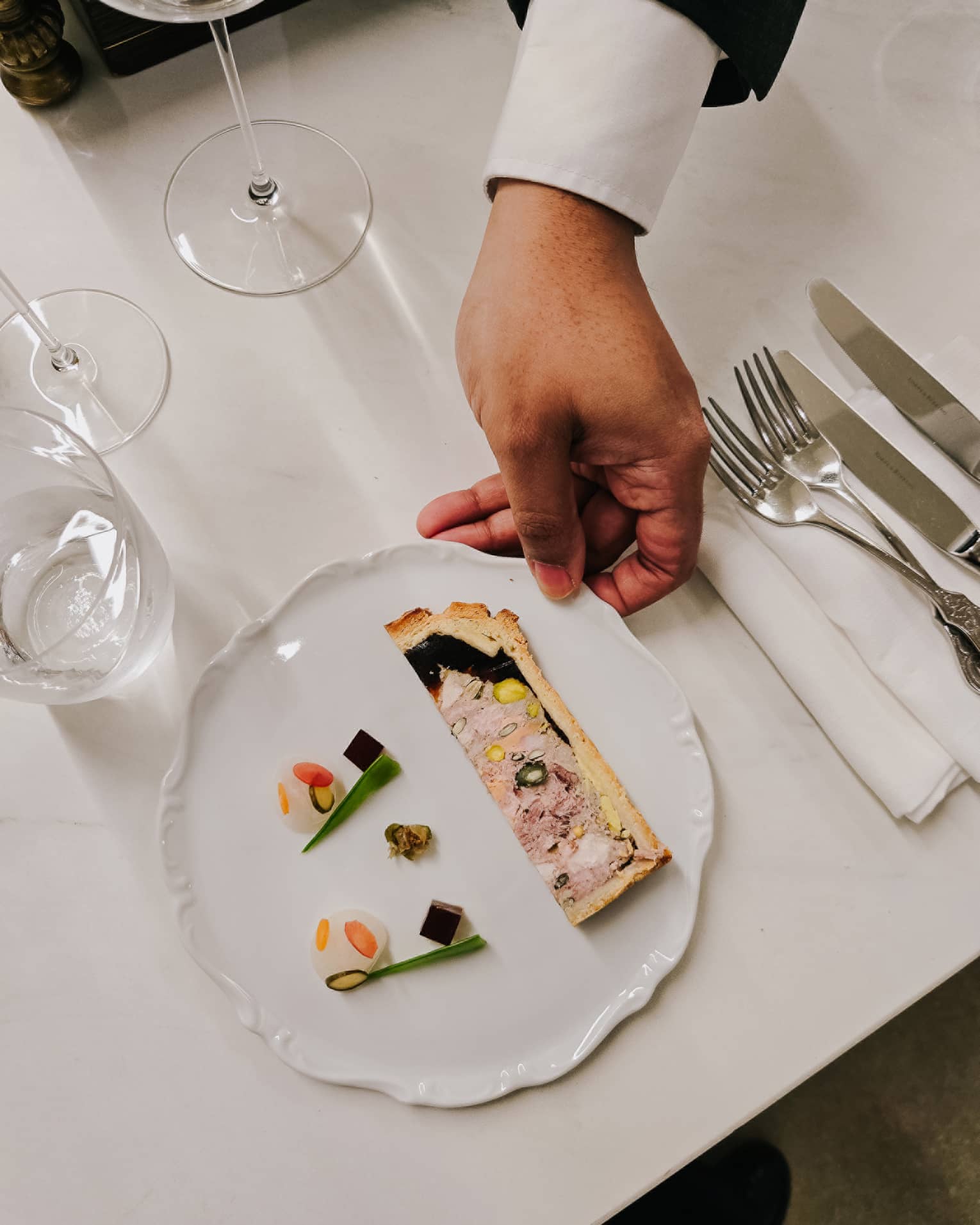 A culinary dish with silverware and wine glasses on the side