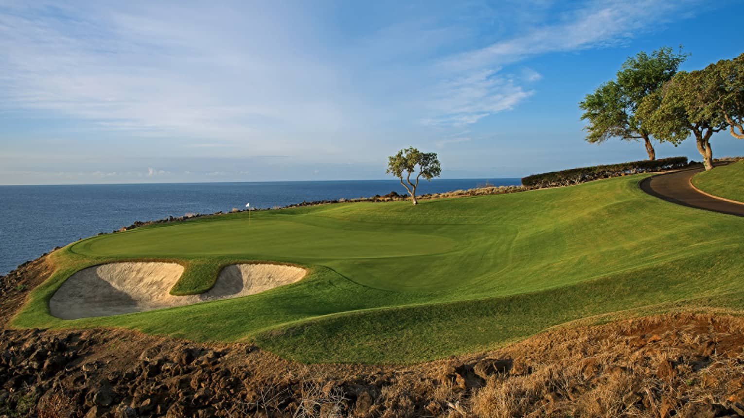 An oceanside golf course under blue skies