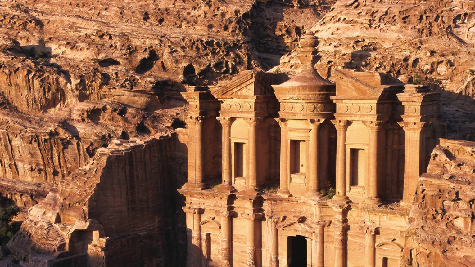 Sunlight across Petra ancient buildings carved into red rock