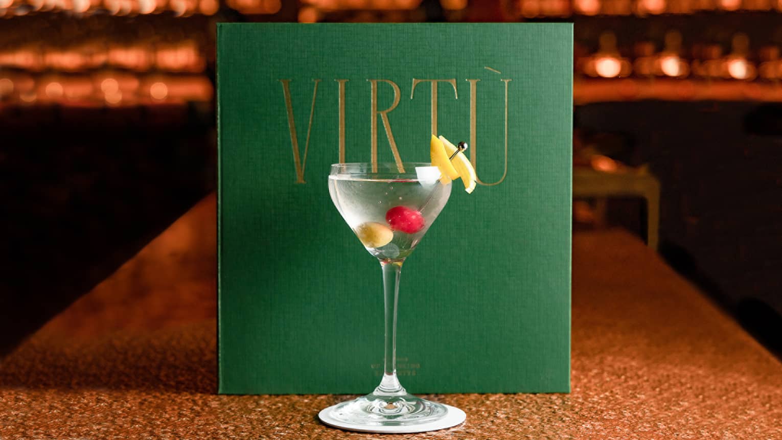 VIRT� Martini with skewer of olives in front of green VIRT� menu