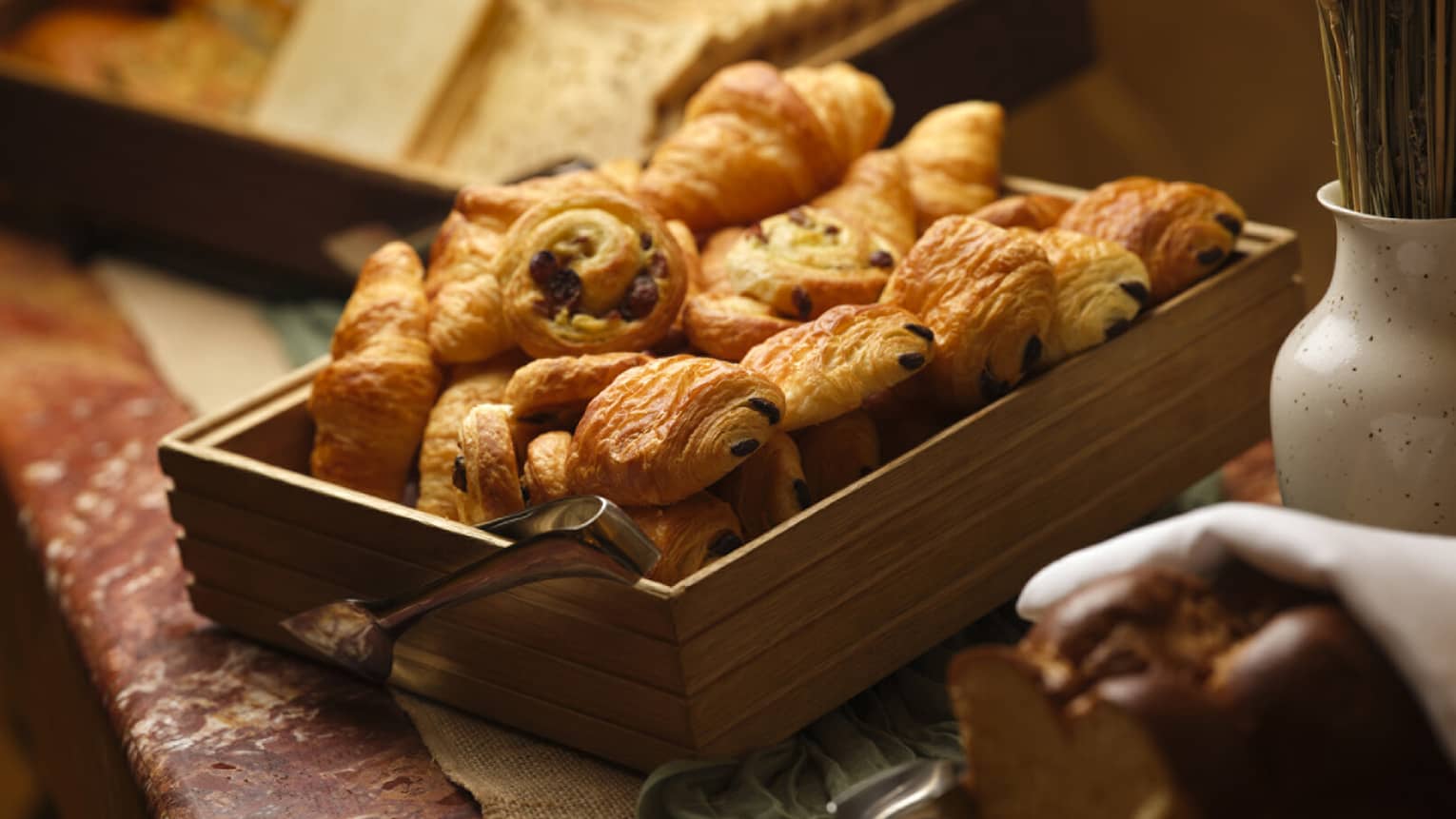 A wooden serving container filled with various croissants