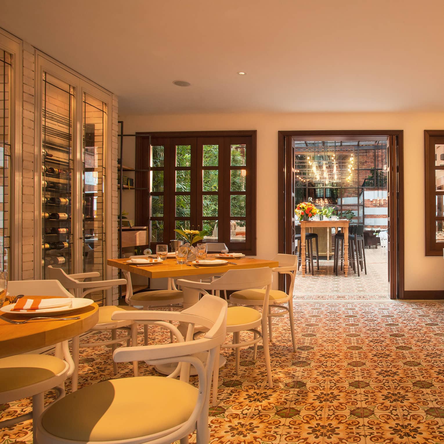 A dining room with mosaic tiles on the floor and walls, and double doors leading out to a patio.