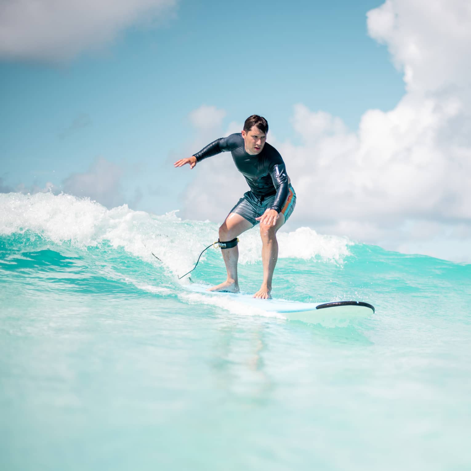 Man balances on surf board over wave