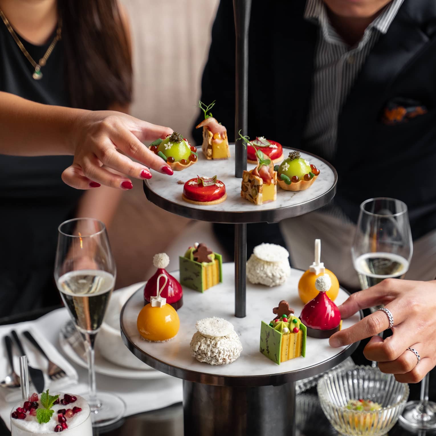 A group of people reach for sweets on two-tiered display tower