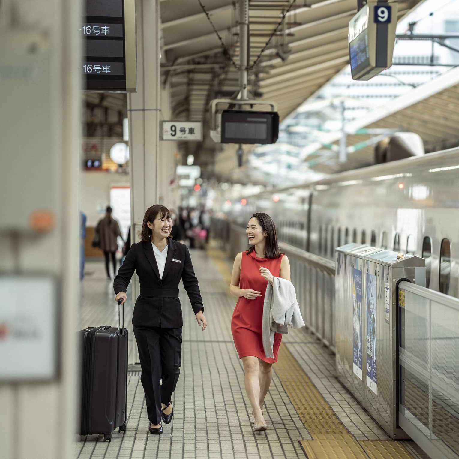 Train station greeter walks with female guest along the train platform