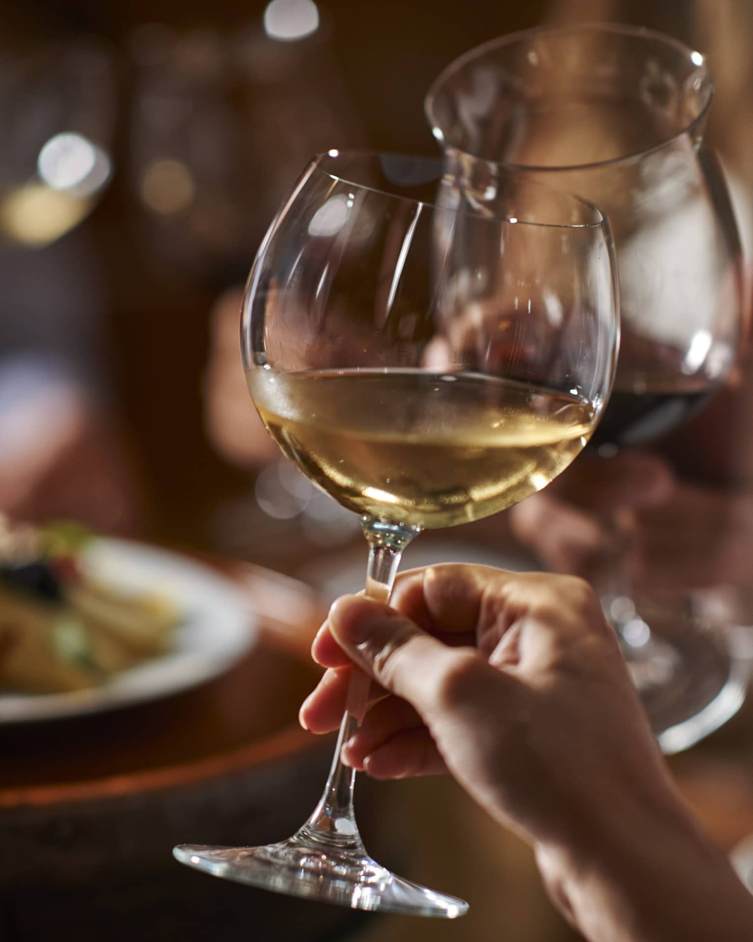 Two guests clink their wine glasses together at dinner