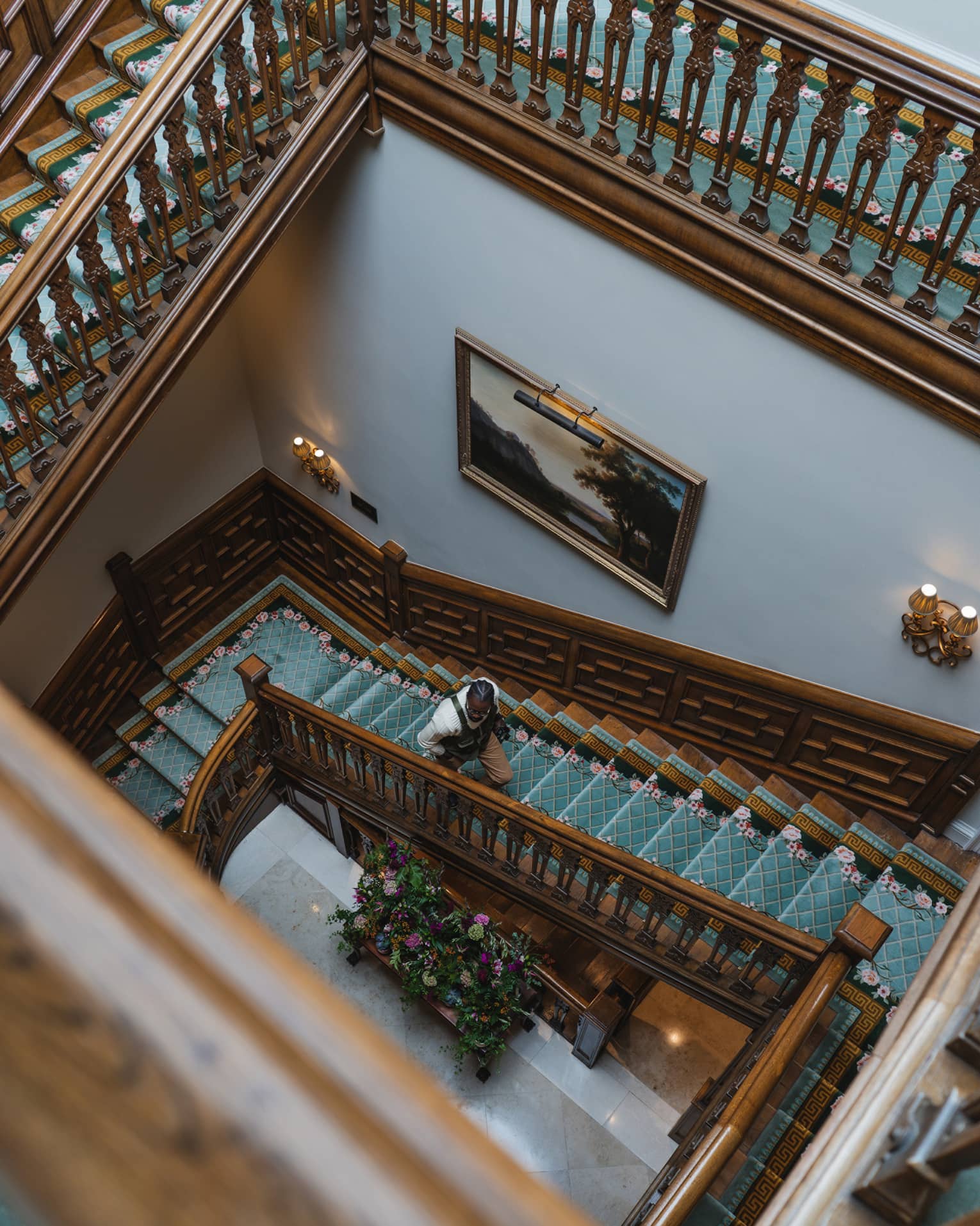 A rectangular wood spiral staircase with a teal blue runner