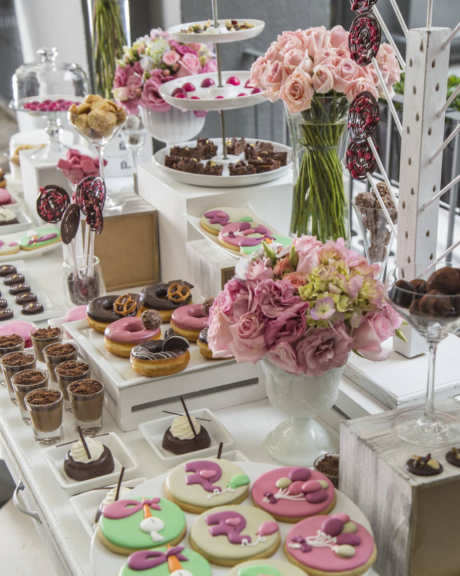 A table with cookies, donuts, cakes and bouquets of flowers