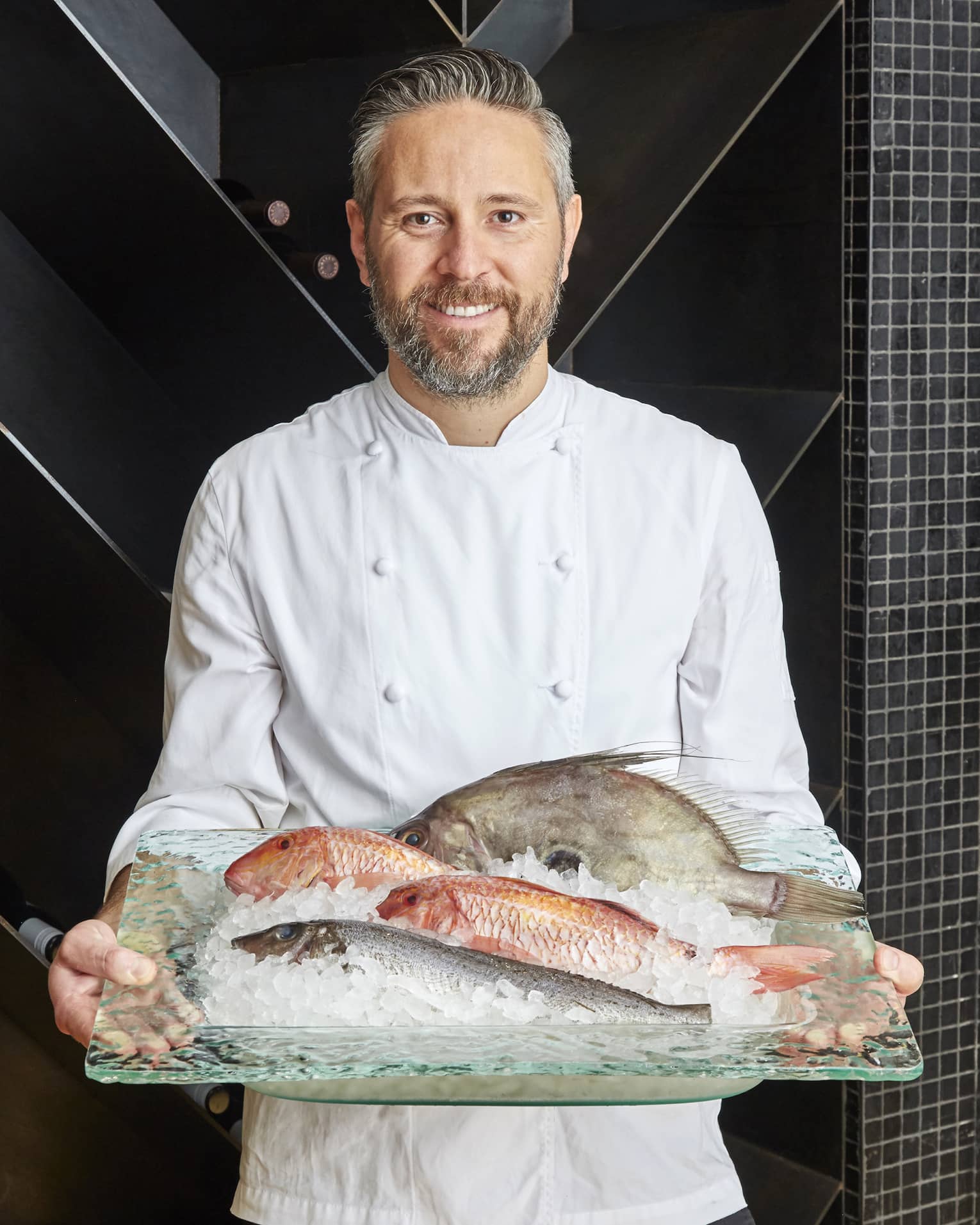 Chef Francesco Mannelli holds a platter of fish on ice