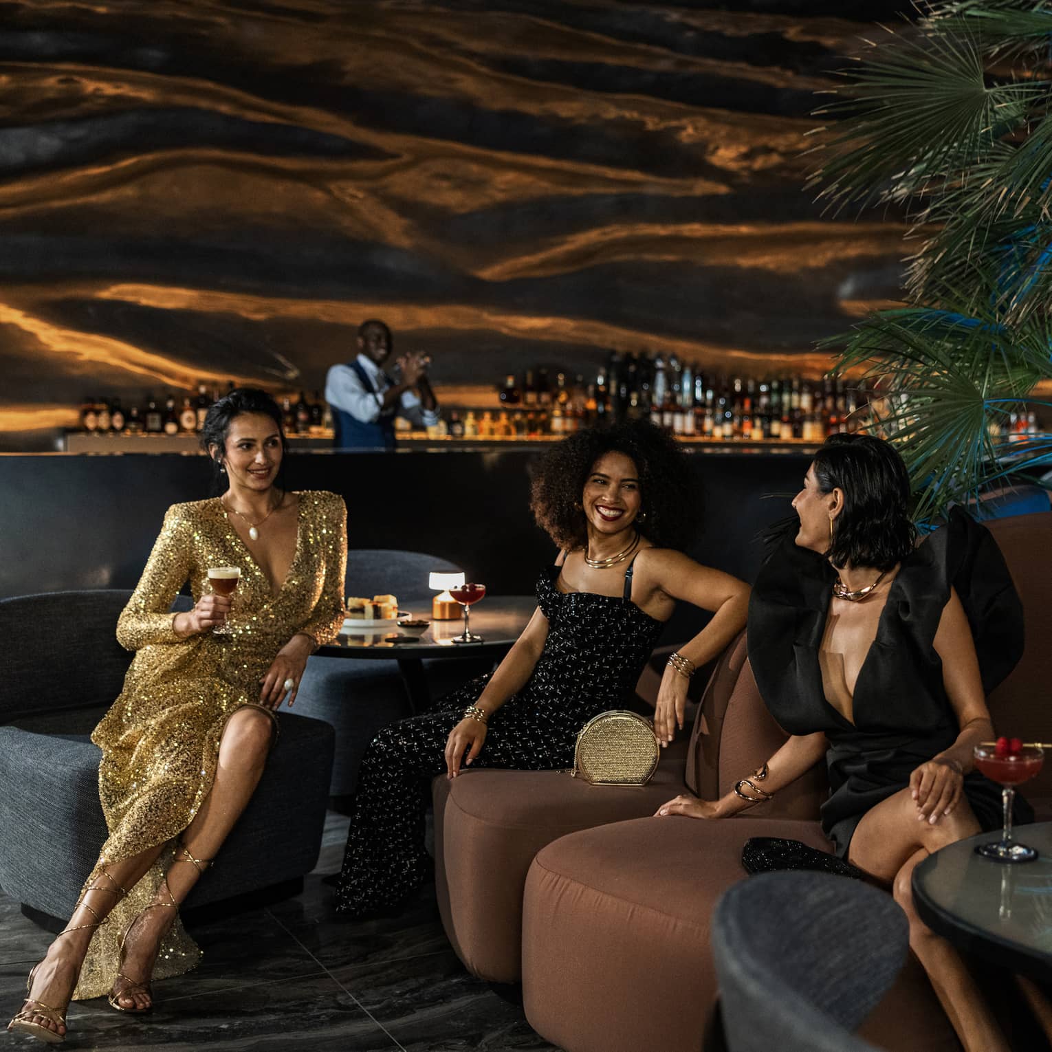 Three women and one man mingle over cocktails at Dubai hotel rooftop lounge