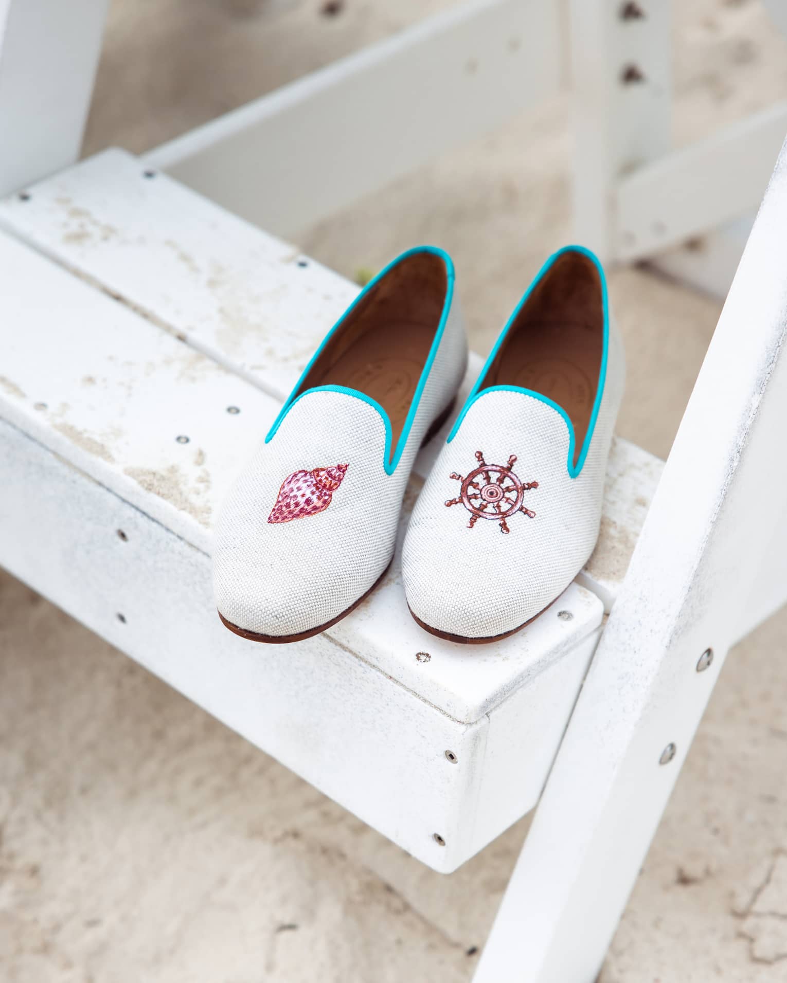 Stubbs & Wootton loafers with nautical embroidery placed on a white wooden step 